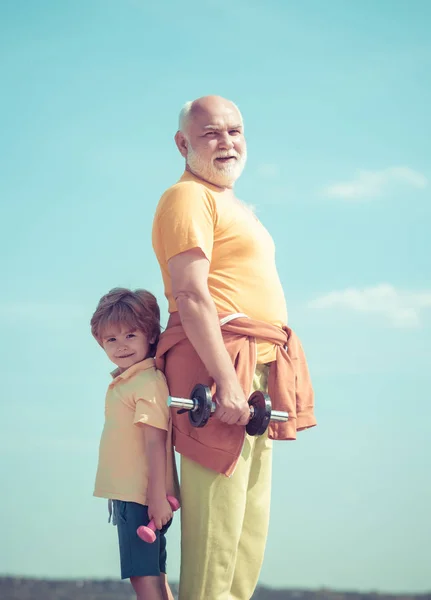 El abuelo y el niño hacen ejercicio matutino. Abuelo e hijo haciendo ejercicios. Vida sana y concepto deportivo . — Foto de Stock