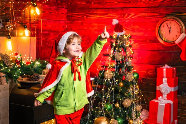 Çocuklar için sihirli Noel gecesi. Noel ağacının yanında gülümseyen küçük çocuk. Küçük çocuk Noel Baba kıyafeti giyiyor. Noel konsepti. — Stok fotoğraf