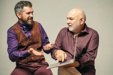 Resmi takım elbiseli yakışıklı iş adamı dizüstü bilgisayar kullanıyor. İş adamlarının portresi. Genç iş adamı dizüstü bilgisayarın nasıl kullanılacağını gösteriyor. Küçük bir iş adamı ekibi..