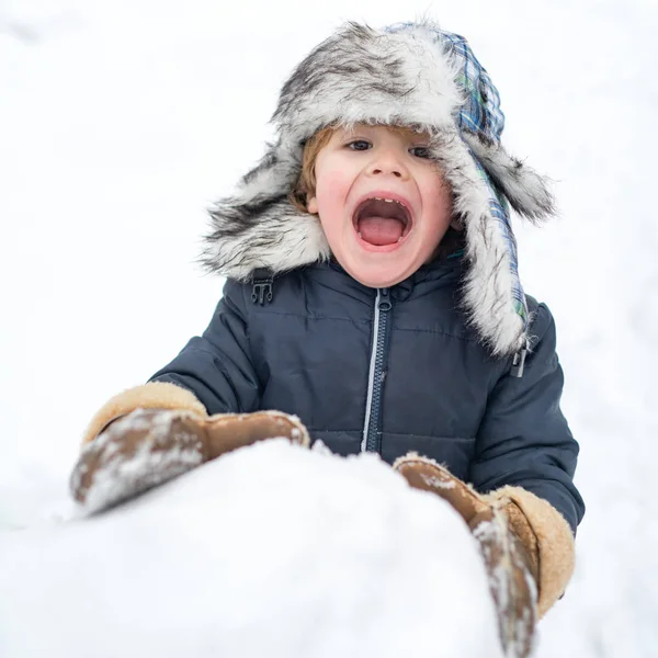 Joyeux enfant jouant avec un bonhomme de neige lors d'une promenade hivernale enneigée. Joyeux hiver. Des gens dans la neige. Profiter de la nature hivernale . — Photo