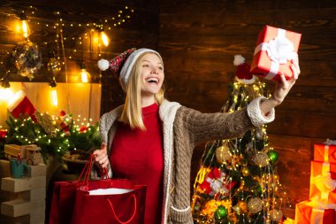 Noel kızı elindeki Noel hediyesine bakıyor. Yeni yıl konsepti. Mutlu kadın. Güzel Noel mankeni kız elinde Noel hediyesi tutuyor.