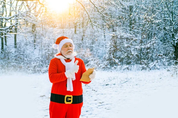 Papá Noel leyendo la carta de Navidad a Papá Noel. Carta de lectura de Santa Claus a Santa Claus en bosque natural de nieve. —  Fotos de Stock