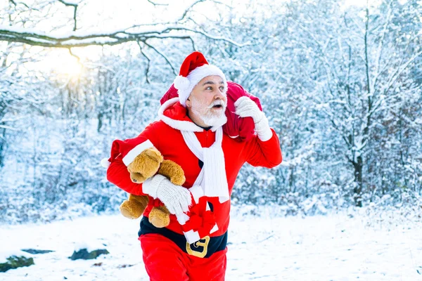 Echter Weihnachtsmann mit roter Mütze, der einen großen roten Geschenksack zieht. Weihnachtsfeier. Frohe Weihnachten und ein gutes neues Jahr. — Stockfoto