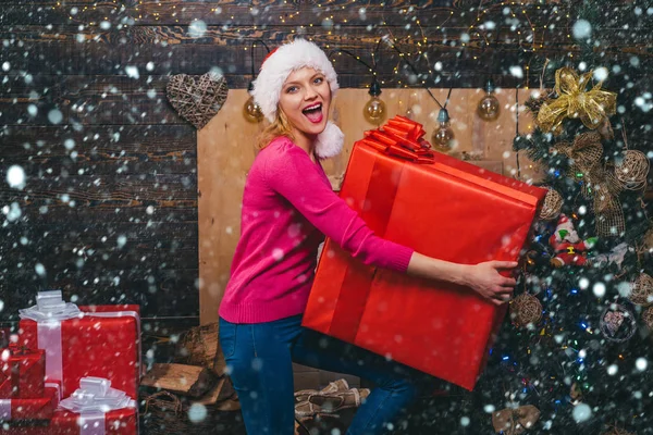 Grande presente de Natal. Mulher de chapéu vermelho de Santa segurando presente. Preparação de Natal. Menina de luxo comemorando Ano Novo . — Fotografia de Stock