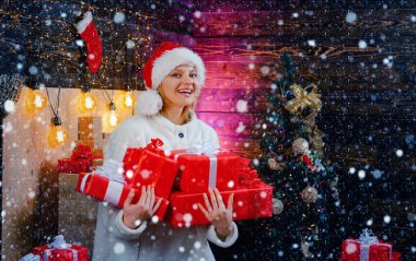 Evinde Noel hediyesi olan güzel bir kadın. Noel Şapkalı Güzellik Modeli Kız ev dekorasyonu üzerine. Noel ve Noel hediyeleri aşkına. Duygular. Noel elbiseleri. Mutlu kadın..