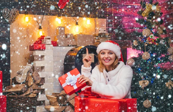 Glada ung kvinna bär juldräkt över trävägg. Vinter semester och människor koncept. Äkta känslor. ung kvinna med julklappslådor framför julgranen. — Stockfoto
