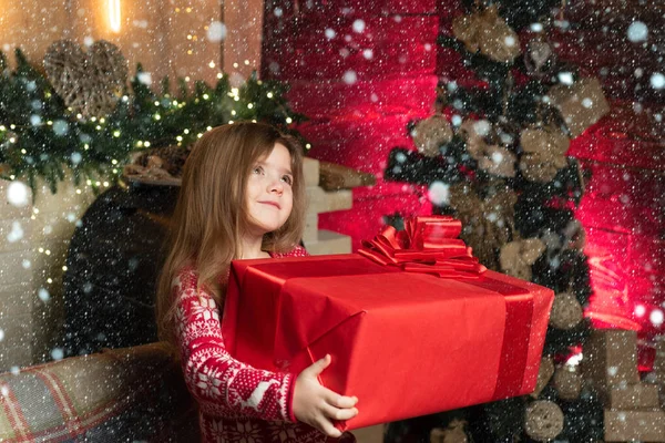 Neşeli şirin çocuk Noel hediyesini açıyor. Küçük kız hediyesini minnettar bir yüzle sunar. Noel 'in gerçek neşesi. — Stok fotoğraf