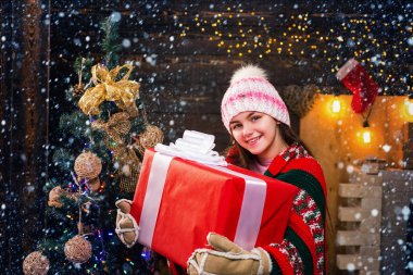 Bir Noel hediyesi ahşap arka plan ile mutlu küçük kız. Yeni yıl kutlama mutluluk çocuk. Kızını üst üst nesneden tutun. Noel hikaye kavramı.