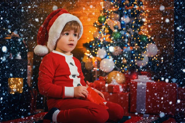 Bonito criança abrir presente de Natal. Bebê adorável desfrutar de Natal. O inverno da criança do menino Papai Noel comemora em casa. Menino bonito criança alegre humor jogar perto da árvore de Natal. Feliz e brilhante Natal — Fotografia de Stock