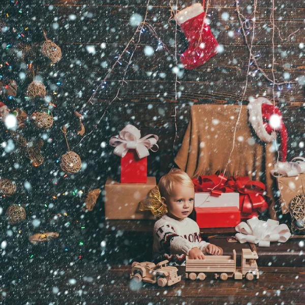 クリスマスの子供たちクリスマスプレゼントを持っている面白い子供。クリスマスと新年にプレゼントを開きます。クリスマスカード木製の背景に贈り物を持つ肖像画の子供. — ストック写真