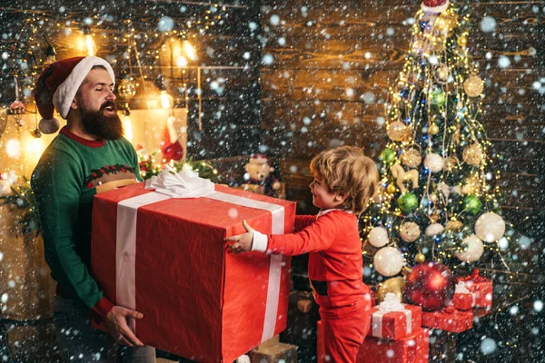 Interni natalizi. Bambino felice con regalo di Natale. Allegro bambino carino aprire un regalo di Natale. Buon figlio e padre con scatola regalo di Natale rossa . — Foto Stock