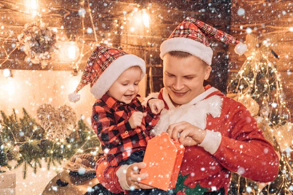 Feliz Natal e Feliz Ano Novo para Pai e filho. O pai vai abrir um presente de Natal com o filho mais novo. Tempo de Natal. Feliz família de Natal . — Fotografia de Stock