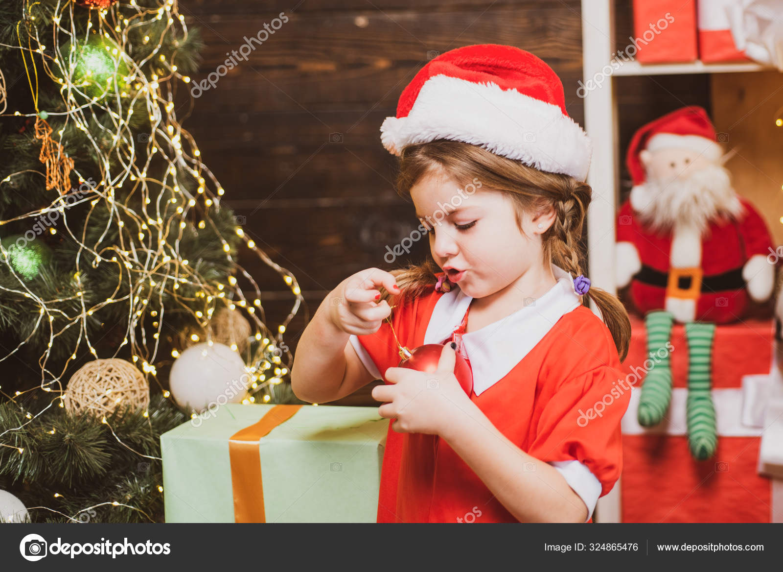 Happy little child dressed in winter clothing think about Santa