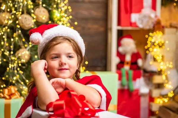 Pequeno presente de presente da menina Papai Noel. Um miúdo engraçado a segurar um presente de Natal. Criança bonita perto da árvore de Natal. Emoção de Natal inverno. — Fotografia de Stock