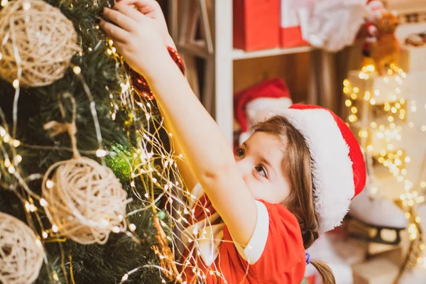 Kerst kind versiert kerstboom met kerstballen. Mooie vrouw versieren kerstboom met kerstbal - Nieuwjaarstraditie. — Stockfoto