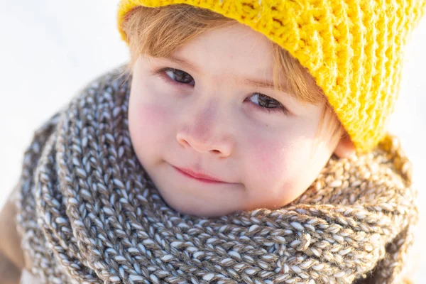 Netter kleiner Junge in Winterkleidung, der unter Schnee spaziert. Kind in blauer Jacke und gelbem Hut geht durch den verschneiten Wald und lauscht den Geräuschen der Natur. Helle Kleidung für Kinder. — Stockfoto