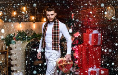 Kardaki Noel adamı. Hediye kutusu sürprizi olan yakışıklı bir adam geceyarısını bekliyor. İyi tatiller. Hediye kartı konsepti. Mutlu yıllar. Noel arifesi. - Eve. Noel hediyeleri. Noel kutlaması gelenekleri.