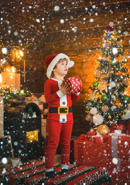 雪の中のクリスマスの子供たち。新年の明るいインテリア。男の子かわいい子供陽気な気分はクリスマスツリーの近くで再生します。屋内だ喜びと幸福。クリスマスショッピングのコンセプト。休日と冬の子供時代のコンセプト — ストック写真