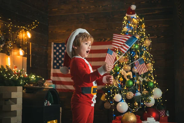 Wesołych Świąt w Ameryce. Świąteczny dzieciak z flagami USA. Boże Narodzenie w Stanach Zjednoczonych. — Zdjęcie stockowe