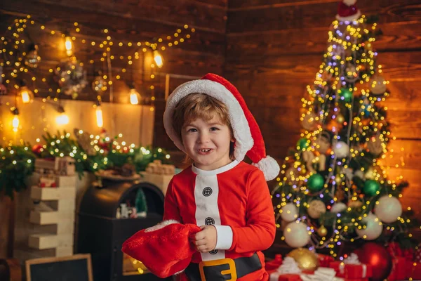 Kerst jongen. Gelukkige kleine lachende jongen met kerstcadeaus sokken. gelukkig kind hebben plezier met cadeau. — Stockfoto