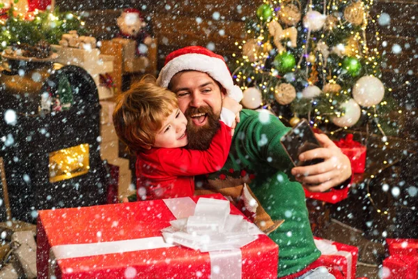 雪の中のクリスマスファミリー。サンタと古い髭サンタはスマートフォンを使用しています。冬のクリスマスの感情。インターネット、ワイヤレス、ソーシャルメディアの概念. — ストック写真