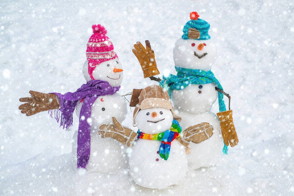 Happy snowman couple and snowman child with Christmas gift standing in winter Christmas landscape. Merry Christmas and happy New Year.