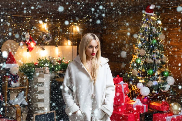 Donna nella neve. Bellezza ragazza di moda con scatola regalo di Natale. La ragazza è felice per il nuovo anno. Donna in abito da sera sopra casa Albero di Natale sfondo . — Foto Stock