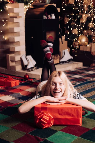 Happy woman is lying on the floor with a gift. Christmas time. Very beautiful blonde girl over Christmas tree. — Stock Photo, Image