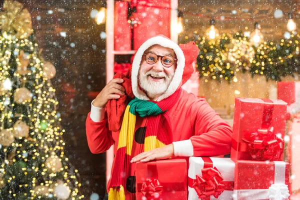 Christmas man in snow. Funny Santa hold Christmas gift. Santa old man posing on vintage wooden background. Theme Christmas holidays and winter new year. Merry Christmas and happy New Year.