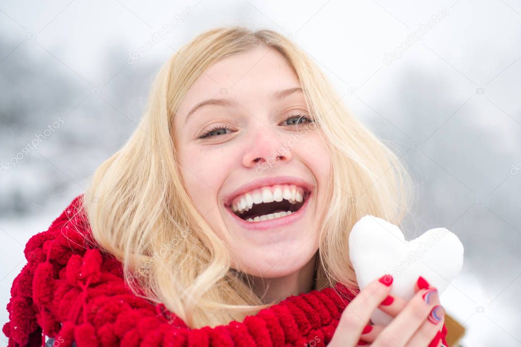 Girl in mittens hold snowball. Portrait of a happy woman in the winter. Cheerful girl outdoors. Cute playful young woman outdoor enjoying first snow.
