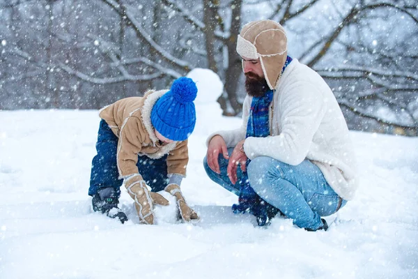 Christmas family in snow. Father and son making snowman. Christmas holidays and winter new year with father and son. Winter family in frosty winter Park. Thanksgiving day and Christmas.