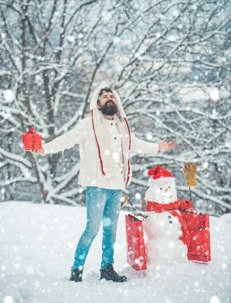 Hombre de Navidad en la nieve. Feliz Navidad y Feliz Año Nuevo. Estilo de Santa hipster con una larga barba posando sobre el fondo de nieve de Navidad . — Foto de Stock