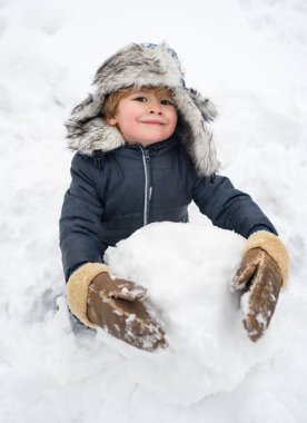 Kardan adam ve komik çocuk arkadaş kırmızı burunlu, kış şapkası ve eşarbıyla dikiliyor. Neşeli çocuk Winter Park 'ta kardan adamla eğleniyor. Çocuklar için kış giysileri.