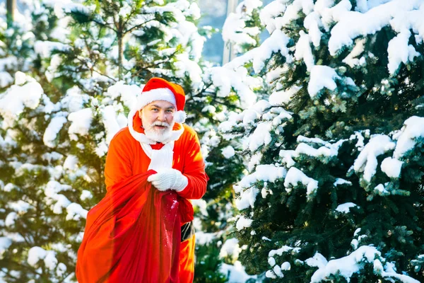 Kerstman op kerstavond draagt cadeautjes aan kinderen in een rode tas. Vrolijk Kerstfeest en Gelukkig Nieuwjaar concept. Kerstviering vakantie. — Stockfoto