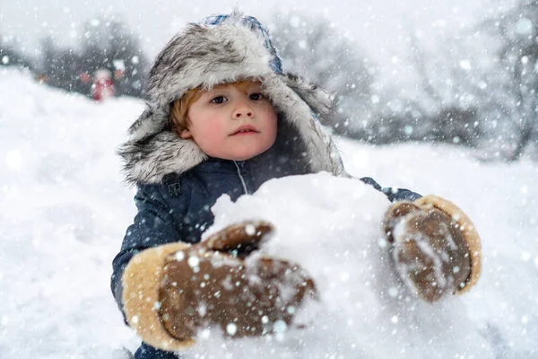 雪の中のクリスマスの子供たち雪原の屋外でかわいい子供の男の子。冬の公園で楽しんでいる子供の男の子。幸せな笑顔の男の子子供作る雪だるまで晴れた冬の日. — ストック写真