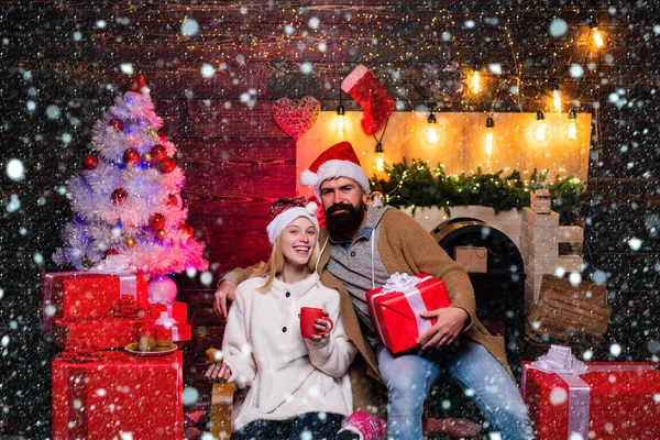 Julpar i snö. Nyårsfamilj med julklapp framför julgranen. Snygg skäggig hipster Santa med leende positiv ung kvinna. Begreppet uttryck och människor. — Stockfoto