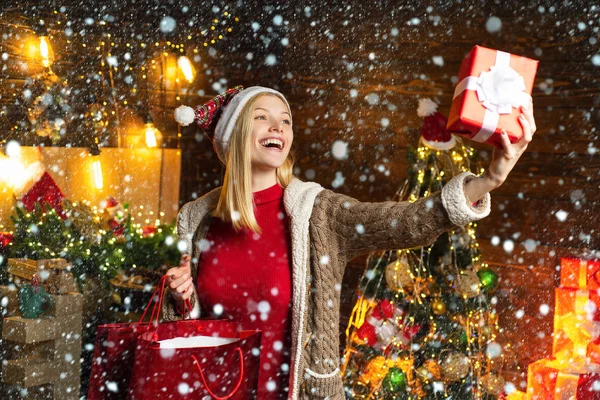 Mulher na neve. Menina de Natal está olhando para o presente de Natal em sua mão. Conceito de ano novo. Uma mulher feliz. Beleza modelo de moda de Natal menina segurando presente de Natal . — Fotografia de Stock