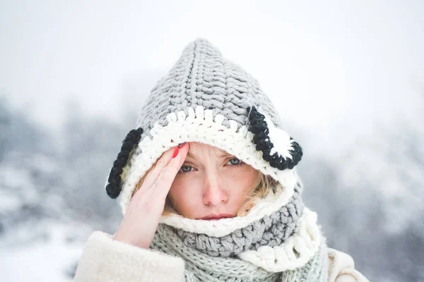 Alergia temporada de invierno. Retrato de una hermosa rubia joven tocando sus sienes sintiendo estrés, sobre fondo nevado de invierno —  Fotos de Stock