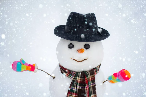 Hóember a barát áll a téli kalap és a sál piros orral. Aranyos kis hóember odakint. Hóember elszigetelve a hófalakon. Hóember a hóban. — Stock Fotó