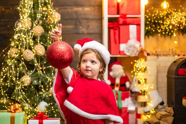 Criança de Natal decoração com bugiganga ou bola de Natal. Brinquedo de Natal - menina está decorando a árvore de Natal . — Fotografia de Stock