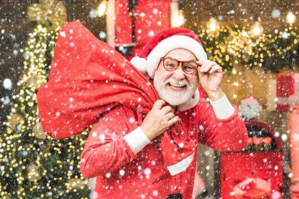 Man in snow. Bearded man having fun near Christmas tree indoors. Santa winter portrait. Christmas preparation - Santa grandpa celebrating New Year. — Stock Photo, Image