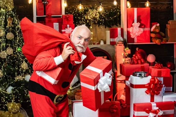 Ladrón pícaro con ropa de Santa y máscara llevando su botín en una bolsa roja. Escena del crimen de vacaciones - ladrón vestido de Santa Claus con un sombrero de Santa Claus . —  Fotos de Stock