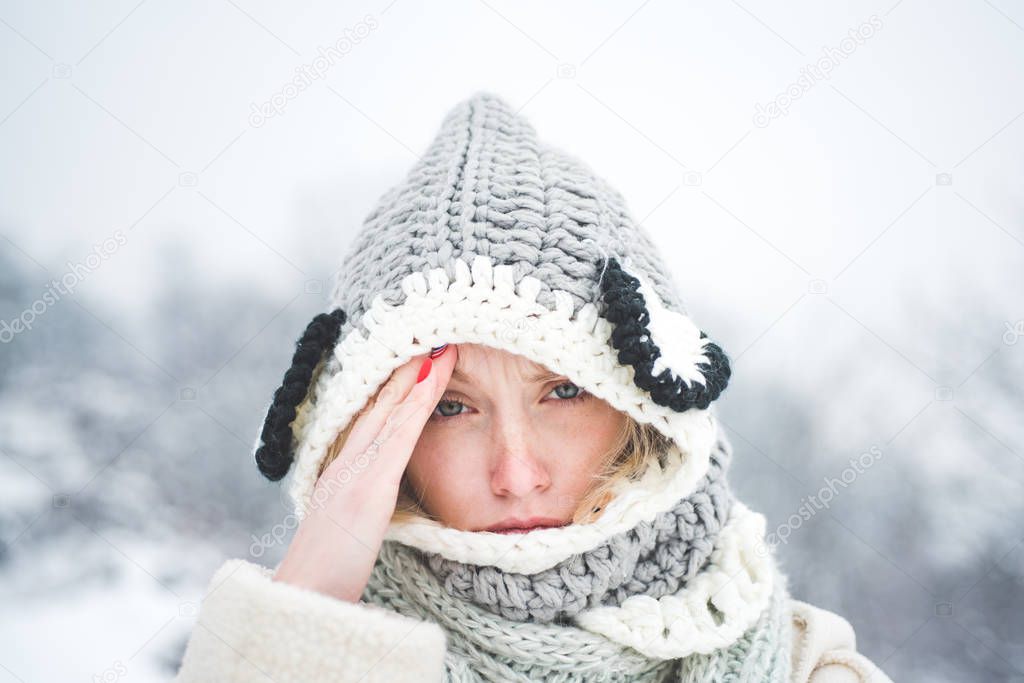 Allergy winter season. Portrait of beautiful young blonde touching her temples feeling stress, on snowy winter background