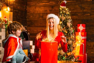 Noel 'de erkek ve kız kardeş. Kadın ve küçük çocuk evi Noel ışıklarıyla süslüyorlar. Noel ağacı arkaplanı. Mutlu aile