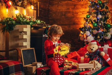 Çocuklar tatilin tadını çıkarır. Hediye duyguları. Noel 'i kutlayan şirin çocuklar. Mutlu yıllar. Noel Baba 'nın portresi kameraya bakıyor..
