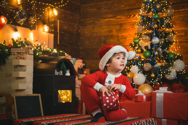 両手で赤いギフトボックスを持っている幸せな子供。クリスマス前の朝だ。クリスマスお祝いの休日。新年のクリスマスのコンセプト. — ストック写真
