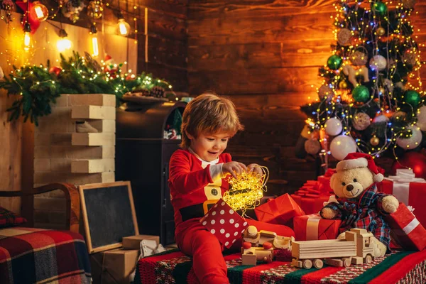 Děti si užívají svátky. Dárkové emoce. Roztomilé malé děti slaví Vánoce. Šťastný nový rok. Portrét Santa dítě s dárkem při pohledu do kamery. — Stock fotografie