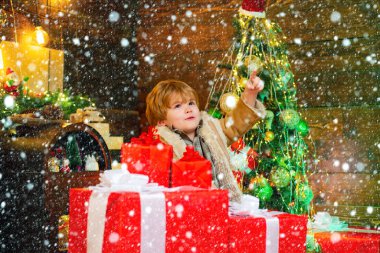 Kardaki çocuk. Neşeli şirin çocuk Noel hediyesini açıyor. Noel hediyesi kutulu mutlu çocuk. Kış çocuğu. Noel hediyesi tutan komik çocuk. Sevimli küçük çocuk Noel ağacını süslüyor.