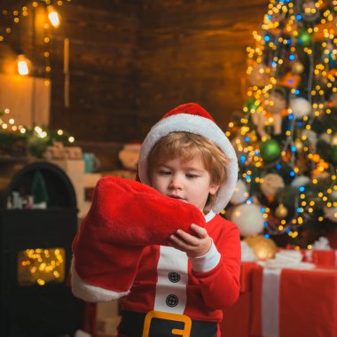 Noel çoraplı çocuk. Noel çocuğu Noel çoraplarına bakıyor. Gülümseyen küçük mutlu çocuk. Tatil kavramı