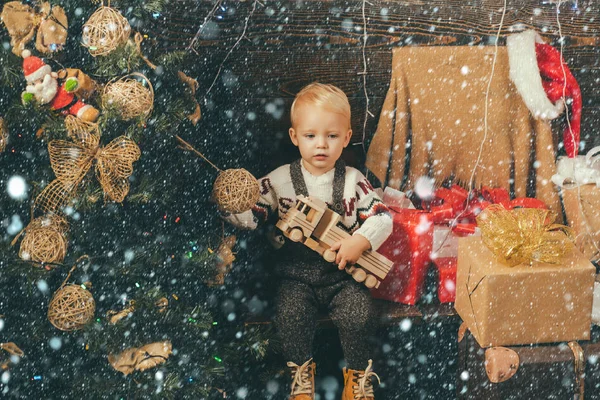 Freudiges Baby, das Weihnachten zu Hause in die Kamera schaut. Kind im Schnee. Eröffnungsgeschenke zu Weihnachten und Neujahr. Weihnachten Weihnachten Winterurlaub Konzept. am Morgen vor Weihnachten. Weihnachten für Kinder. — Stockfoto